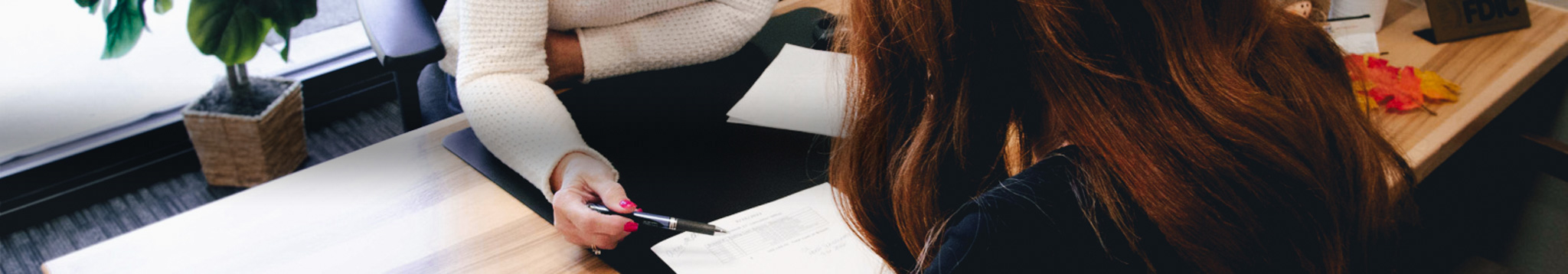 person in office pointing pen at a piece of paper for customer to read